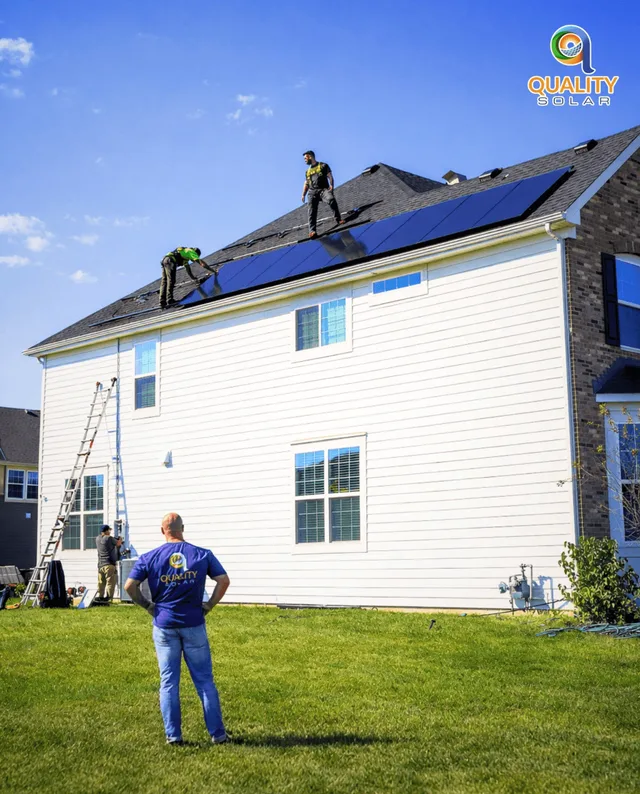 Two solar installers comparing plans on a residential roof