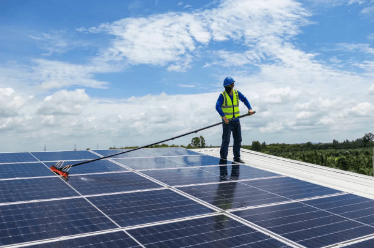 A technician cleaning solar panels on a residential roof
